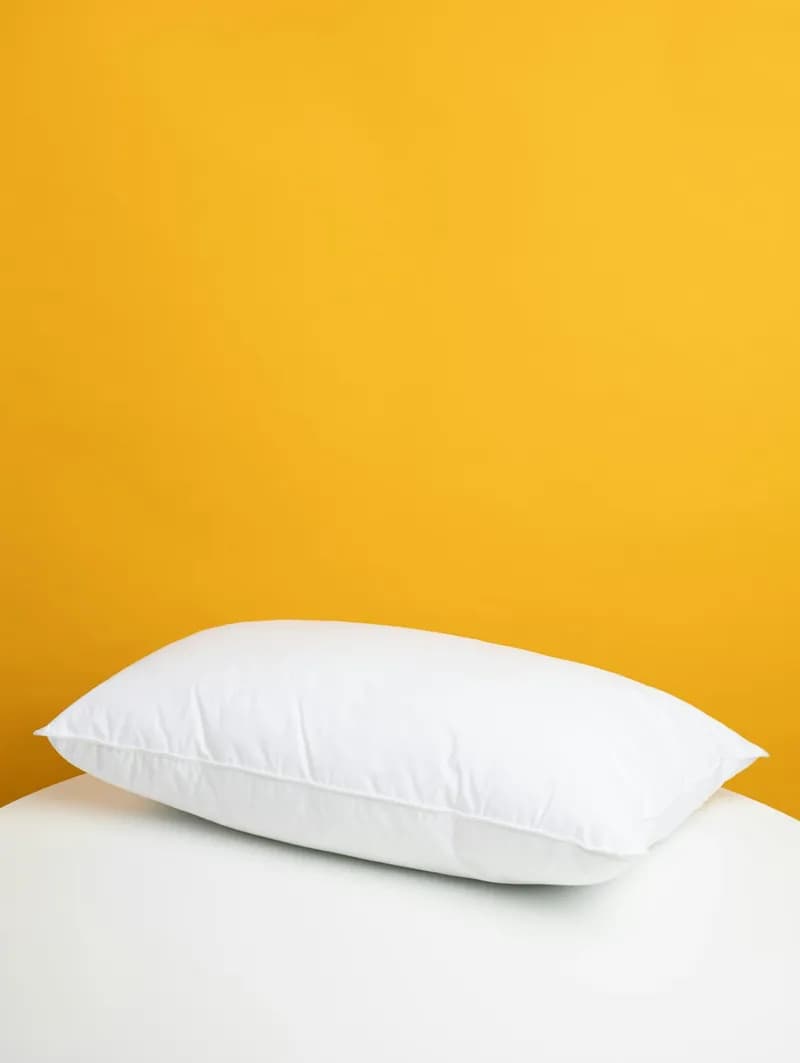 Almohada de fibra blanca sobre fondo amarillo